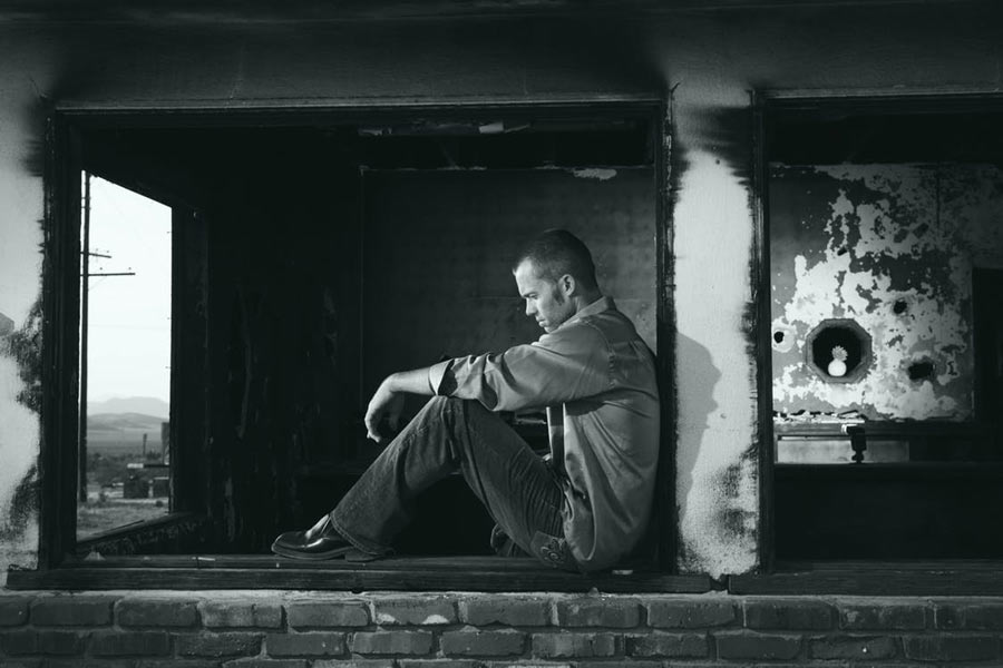 anxiety and depression | b&w photo of a sad man sitting in a window | Dr. Negin Misaghi, ND